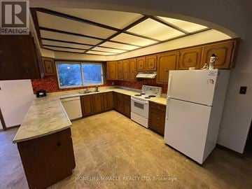 Brampton (Bram West) apartment for rent - A kitchen with a white fridge, white countertop, and brown cabinets.