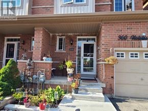 Milton (Cl Clarke) townhouse for rent - A house with a front yard featuring a variety of potted plants.