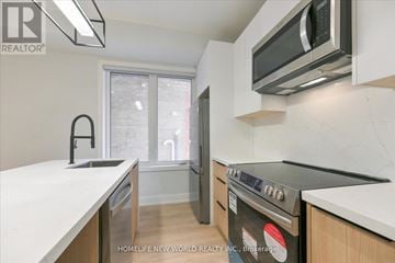 Toronto (Dufferin Grove) townhouse for rent - A modern kitchen with a stove top oven and a microwave above it.