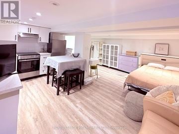 Toronto (Downsview-Roding-Cfb) apartment for rent - A well-lit, spacious bedroom with a large bed and a kitchen area with a stove and oven.