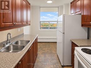 Toronto (Glenfield-Jane Heights) apartment for rent - A kitchen with a white refrigerator, brown cabinets, and a window with a view of trees.