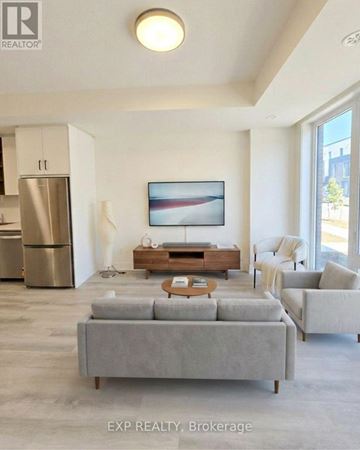 St. Catharines (Oakdale) townhouse for rent - A modern living room with a grey sofa and a painting on the wall.