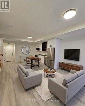 St. Catharines (Oakdale) townhouse for rent - A modern living room with a grey sofa, a wooden coffee table, and a flat-screen TV mounted on the wall.