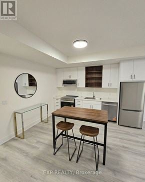 St. Catharines (Oakdale) townhouse for rent - A kitchen with white cabinets and a wooden table.