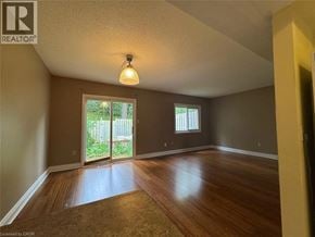 Kitchener townhouse for rent - A room with wooden floors and a sliding glass door leading to a backyard.