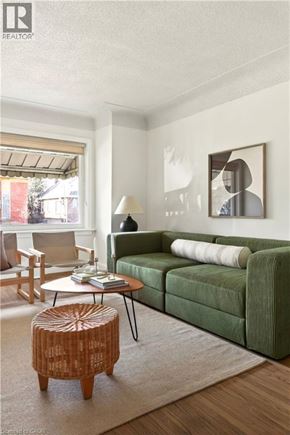 Hamilton apartment for rent - A living room with a green couch, a wooden stool, and a painting on the wall.