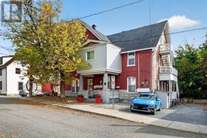 Ottawa multi-family for rent - A blue car is parked in front of a red and white house.