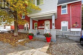 Ottawa multi-family for rent - A red brick house with a white porch and a tree with yellow leaves.