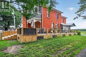 Ottawa apartment for rent - A red brick house with a white porch and a wooden fence.