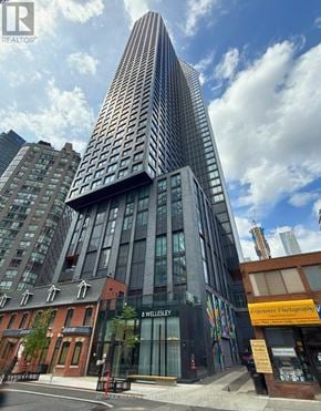 Toronto (Bay Street Corridor) condo for rent - A tall building with a glass facade stands in front of a row of smaller buildings.