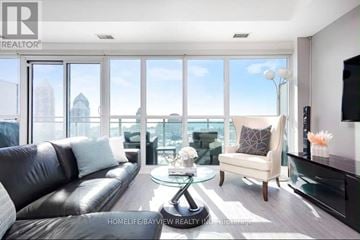 Toronto (Mimico) condo for rent - A living room with a black leather couch and a glass table.