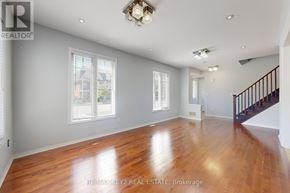 Pickering (Duffin Heights) apartment for rent - A spacious room with wooden floors and a staircase on the right side.