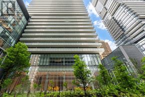 Toronto (Church-Yonge Corridor) condo for rent - A modern building with a glass facade is surrounded by greenery.