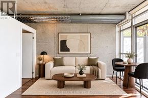 Toronto (South Parkdale) condo for rent - A living room with a white couch, a coffee table, and a painting on the wall.