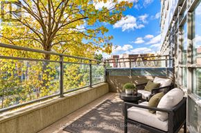 Toronto (South Parkdale) condo for rent - A balcony with a table and chairs overlooking a tree with yellow leaves.