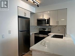 Toronto (Waterfront Communities) condo for rent - A kitchen with a refrigerator, microwave, oven, and sink.
