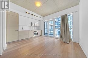 Toronto (Kensington-Chinatown) condo for rent - A spacious room with wooden flooring and a large window with a curtain.