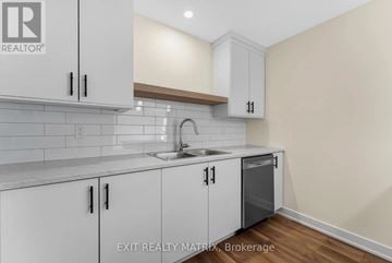 Russell multi-family for rent - A kitchen with white cabinets and a sink.