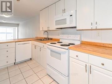 Toronto (Greenwood-Coxwell) multi-family for rent - A white kitchen with a wooden counter top.