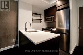 Toronto (South Riverdale) condo for rent - A modern kitchen with a sink, stainless steel refrigerator, and a microwave.