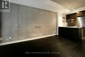 Toronto (South Riverdale) condo for rent - A modern kitchen with a concrete wall and black countertops.