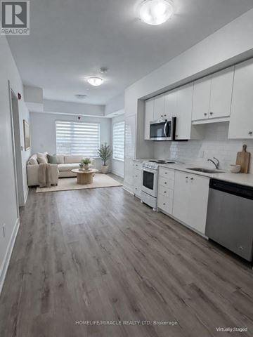Kitchener condo for rent - A modern kitchen with white cabinets and a wooden floor.
