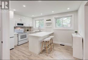 Toronto (Don Valley Village) apartment for rent - A white kitchen with a bar stool and a window.