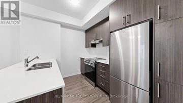 Toronto (New Toronto) townhouse for rent - A modern kitchen with a stainless steel refrigerator and wooden cabinets.