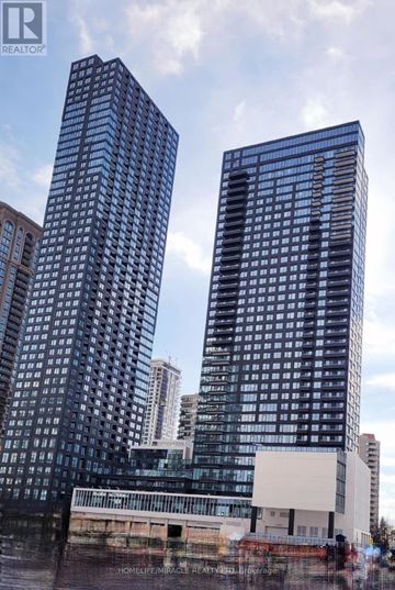 Mississauga (City Centre) condo for rent - Two tall buildings stand next to each other with a cloudy sky in the background.