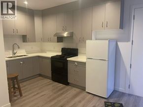 Burnaby apartment for rent - A kitchen with a black stove top oven and white cabinets.