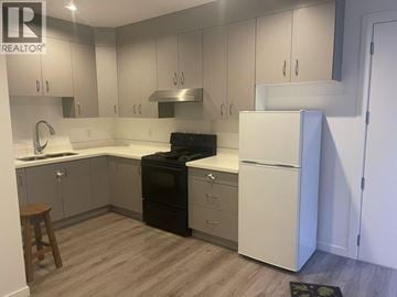 Burnaby apartment for rent - A kitchen with a black stove top oven and white cabinets.