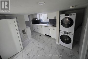 Kitchener duplex for rent - A white kitchen with a marble floor and a washing machine in the corner.