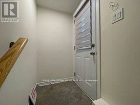 Barrie (Innis-Shore) apartment for rent - A white door with a handle is in a room with a wooden staircase.