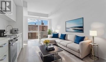 Toronto (Weston-Pellam Park) condo for rent - A modern living room with a large painting on the wall and a view of a building outside the window.