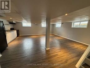 London East (East D) apartment for rent - A spacious room with wooden flooring and white walls, with a black refrigerator on the left side.