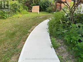 St. Catharines (Vine/Linwell) apartment for rent - A concrete walkway leads through a lush green garden.