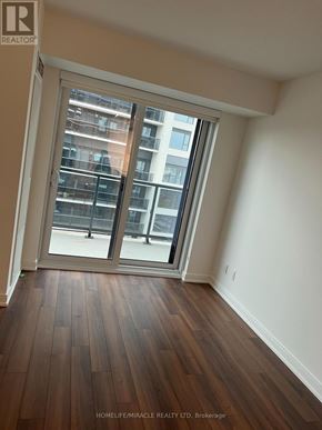 Toronto (Islington-City Centre West) condo for rent - A room with wooden floors and a large window with a view of a building outside.