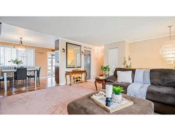 Langley apartment for rent - A living room with a grey couch, a coffee table, and a dining table with chairs.