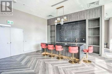 Toronto (Tam O'shanter-Sullivan) condo for rent - A modern kitchen with a bar area and red stools.