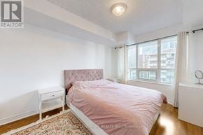 Toronto (Mount Pleasant West) condo for rent - A bedroom with a pink bedspread and a white nightstand.