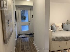 Collingwood condo for rent - A bedroom with a bed, nightstand, and a door with a glass window.