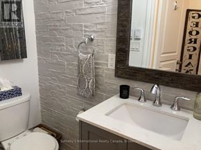 Collingwood condo for rent - A bathroom with a white toilet, a sink, and a mirror.