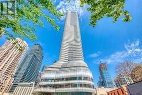 Toronto (Bay Street Corridor) condo for rent - A tall, modern building with a curved glass facade stands in the foreground of a cityscape.