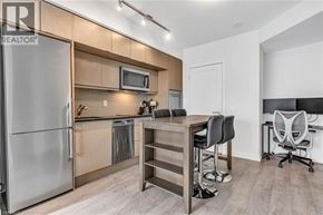 Toronto condo for rent - A kitchen with a refrigerator, microwave, and a dining table with chairs.