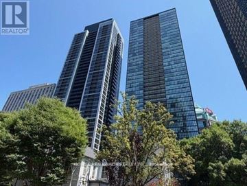 Toronto (Church-Yonge Corridor) condo for rent - A tall building with a glass facade stands among other buildings and trees.