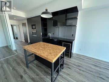 Toronto (Bay Street Corridor) condo for rent - A modern kitchen with a wooden table and black cabinets.