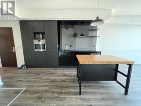 Toronto (Bay Street Corridor) condo for rent - A modern kitchen with a wooden table in the middle.