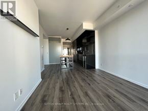 Toronto (Bay Street Corridor) condo for rent - A spacious room with wood flooring and white walls.