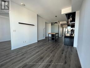 Toronto (Bay Street Corridor) condo for rent - A spacious room with wood flooring and white walls.