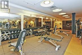 Mississauga (City Centre) condo for rent - A gym with a variety of equipment including dumbbells, weight machines, and a bench press.